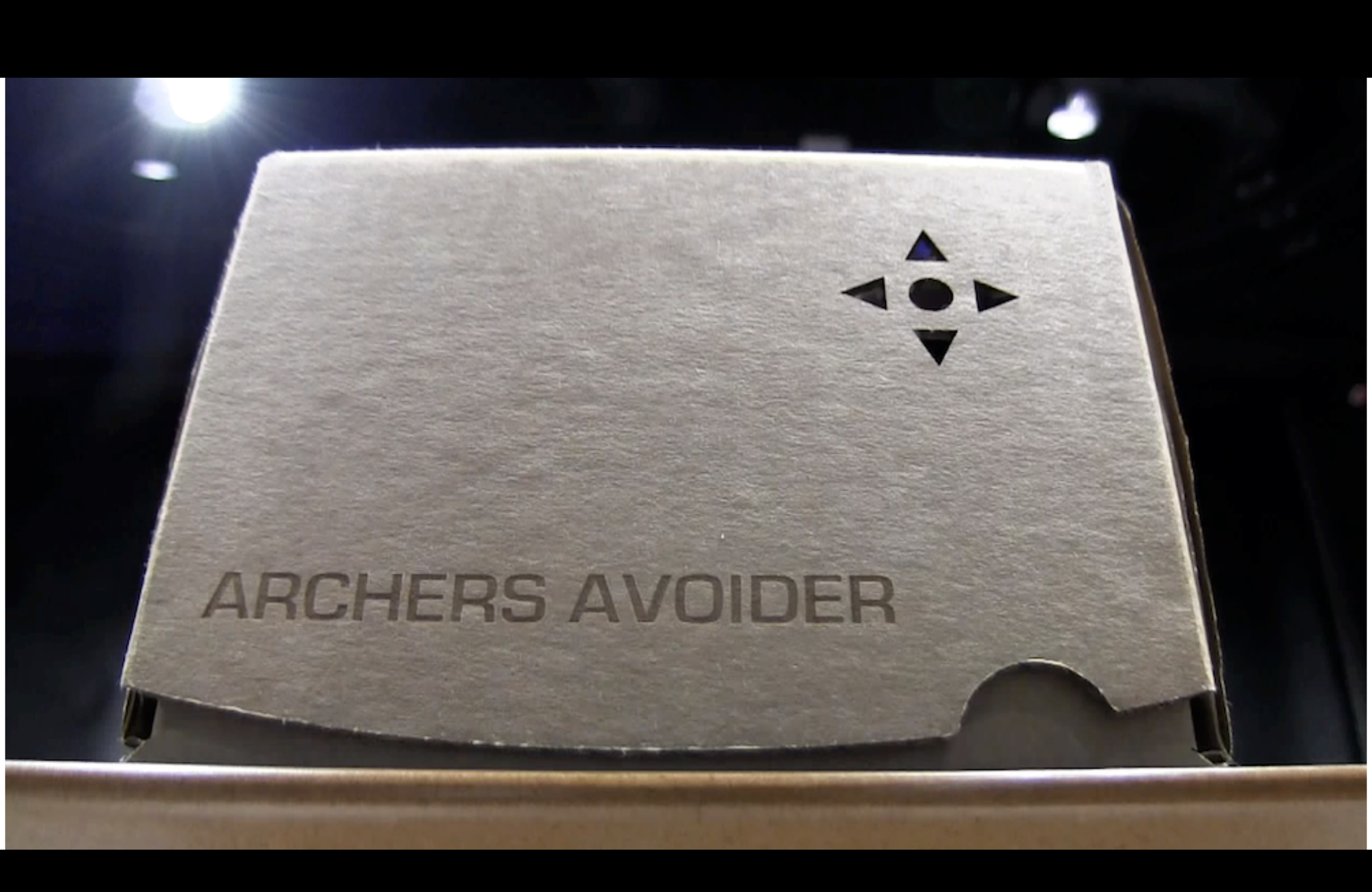 A cardboard archers avoider, lit dramatically from above (it's basically a cardboard box, but with 'archers avoider' lasered into it